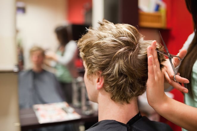 Blond-haired man having a haircut with scissors