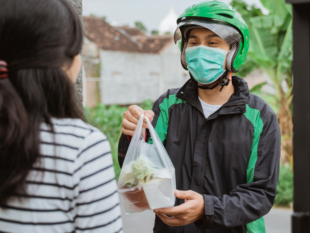 Delivery man delivering grocery bag wearing face mask and gloves